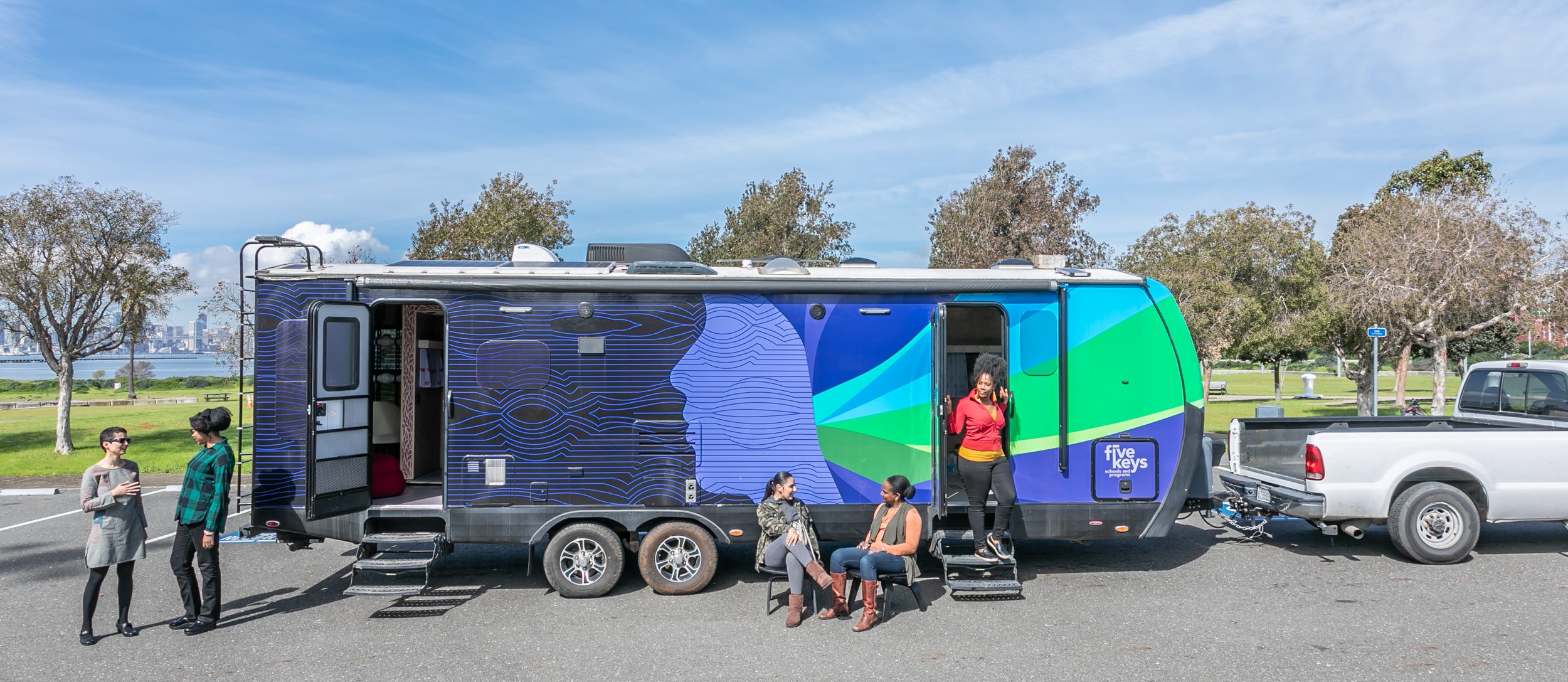 Women sitting and standing in front of trailer